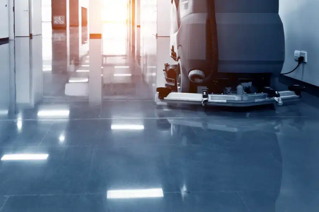 Autolaveuse professionnelle nettoyant un sol brillant dans un couloir industriel moderne et lumineux.